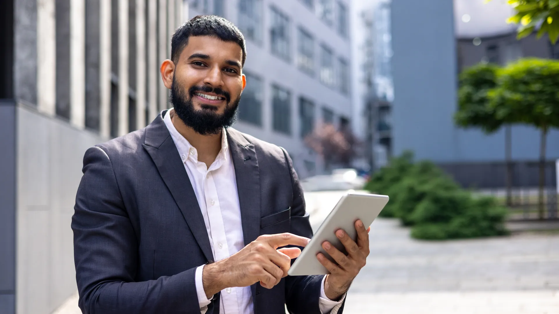 Indian field sales executive using a tablet outside a corporate office