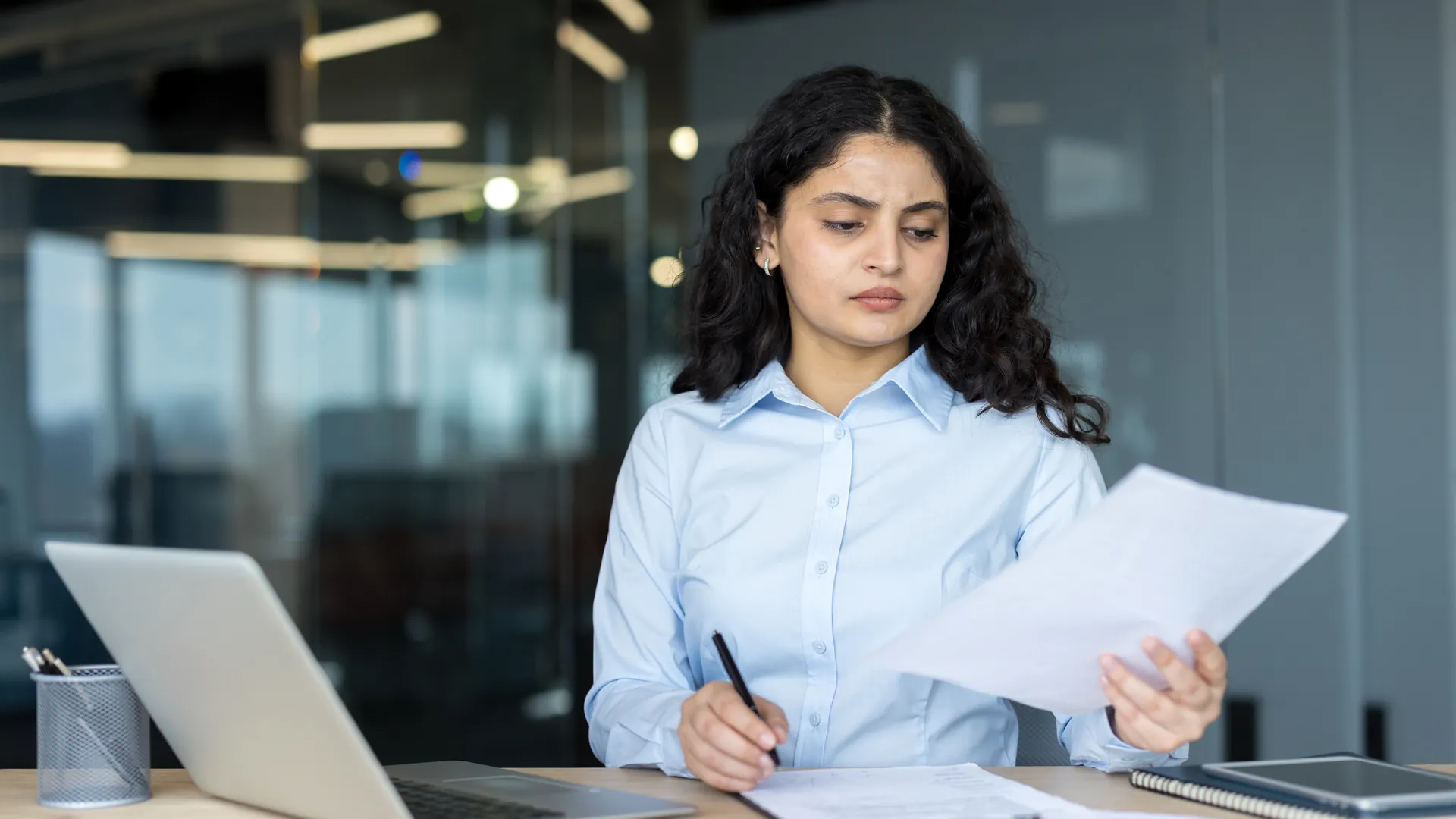 Finance professional reviewing payroll documents at her desk