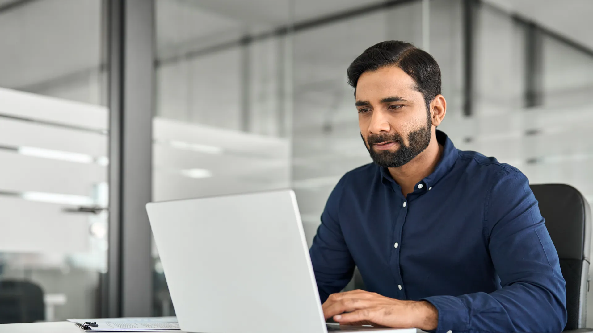 Professional reviewing workforce data on a laptop in a modern office