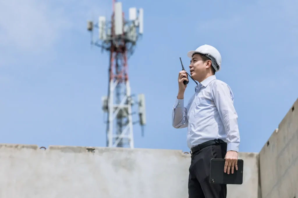 Telecom engineer with a radio beside a mobile tower