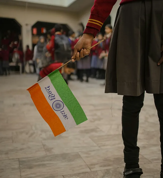 Student holding a small Indian flag at a school assembly